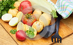 Fresh garden vegetables assorted o woodenn cutting board with kitchen stuff photo