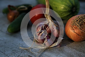 Fresh garden vegetables - garlic, onion, zucchini, tomatoes, cucumber on a light wooden background