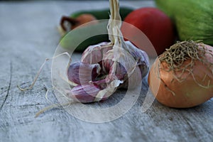 Fresh garden vegetables - garlic, onion, zucchini, tomatoes, cucumber on a light wooden background