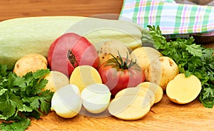 Fresh garden vegetables and herbs on cutting board on wooden background