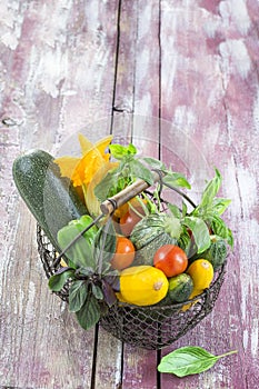 Fresh garden vegetables on iron basket on old purple wooden board