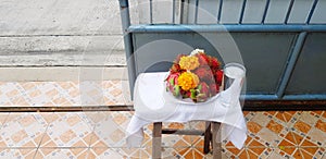 Fresh garland flower with rambutan, dragon fruit and glass of water on table with blue stainless steel fence