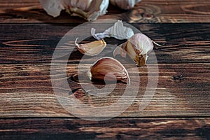 Fresh garlic bulbs and a garlic press on an old wooden board and a burlap backing