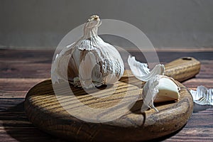 Fresh garlic bulbs and a garlic press on an old wooden board and a burlap backing