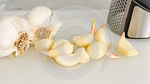 Fresh garlic, and garlic press close-up on white background