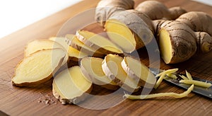 Fresh Ginger Root Yellow Slices and Whole Rhizome on Wood Cutting Board