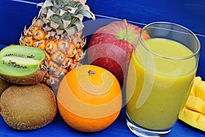 Fresh glass of juice with fruit mix on a wood table