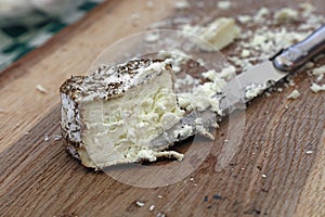 Fresh goat cheese with knife on wooden board