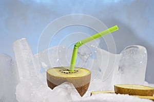 Fresh golden kiwi fruit with a cocktail straw frozen on a cold blue ice.
