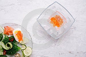 Fresh  gourmet salad with  salmon, caviar, eggs and vegetables. served on white table.   Protein luxury delicacy  healthy food.