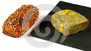 Fresh grain bread and a piece of black bread with green mold on a black shale board isolated on white background, concept of inedi