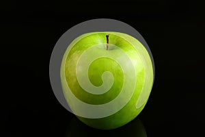 A fresh Granny Smith apple on a black background.