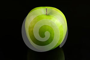 A fresh Granny Smith apple on a black background.