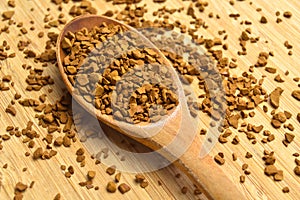 Fresh granules of instant coffee grains, in wooden spoon, on wooden background