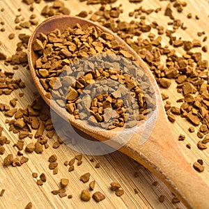 Fresh granules of instant coffee grains, in wooden spoon, on wooden background