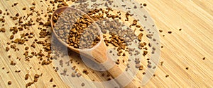 Fresh granules of instant coffee grains, in wooden spoon, on wooden background