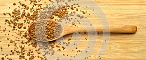 Fresh granules of instant coffee grains, in wooden spoon, on wooden background