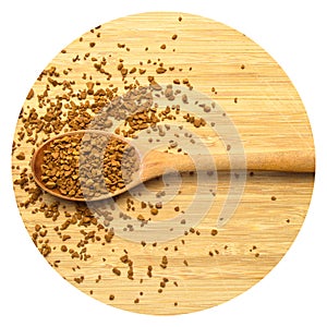 Fresh granules of instant coffee grains, in wooden spoon, on wooden background