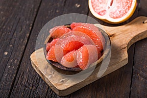 Fresh grapefruit slices in a wooden bowl, healthy snack