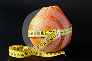 Fresh grapefruit wrapped with measuring tape. The concept of healthy nutrition, weight loss, dietetics