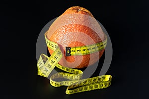 Fresh grapefruit wrapped with measuring tape. The concept of healthy nutrition, weight loss, dietetics