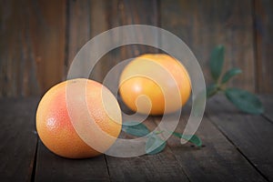 Fresh grapefruits with leaves on wooden background