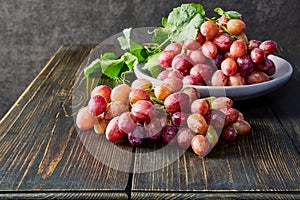 Fresh grapes. Bunches of different varieties in a plate on an old wooden table and dark background.