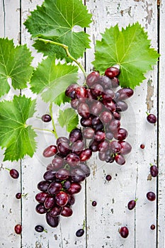 Fresh grapes of redwine on an old white wooden table