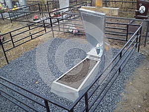 a fresh grave and a gravestone in the cemetery