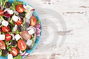 Fresh greek salad with feta cheese and vegetables as healthy meal containing vitamins and minerals. Place for text