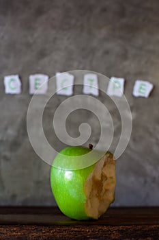 Fresh green apple bitten on a wooden table