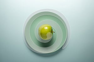 Fresh green apple on a turquoise plate