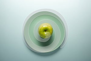 Fresh green apple on a turquoise plate