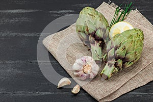 Fresh green artichokes cooking on wooden background. Traditional seasonal ingredients