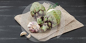 Fresh green artichokes cooking on wooden background. Traditional seasonal ingredients