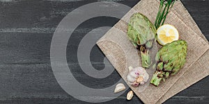 Fresh green artichokes cooking on wooden background. Traditional seasonal ingredients