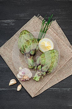 Fresh green artichokes cooking on wooden background. Traditional seasonal ingredients