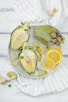 Fresh green artichokes cooking on wooden background. Traditional seasonal ingredients
