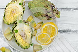 Fresh green artichokes cooking on wooden background. Traditional seasonal ingredients