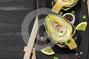 Fresh green artichokes cooking on wooden background. Traditional seasonal ingredients