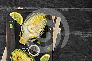 Fresh green artichokes cooking on wooden background. Traditional seasonal ingredients