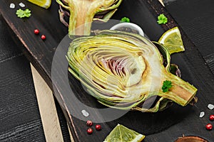 Fresh green artichokes cooking on wooden background. Traditional seasonal ingredients