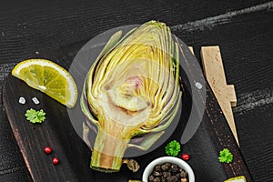 Fresh green artichokes cooking on wooden background. Traditional seasonal ingredients