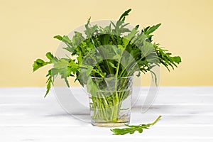 Fresh green arugula salad on glass with water on a wooden table. Simple rustic background, antioxidant and healthy food, Green