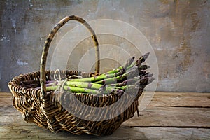 Fresh green asparagus in a basket on a rustic wooden table in fr