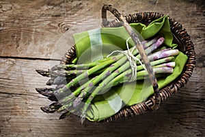Fresh green asparagus in a basket on a rustic wooden table, view