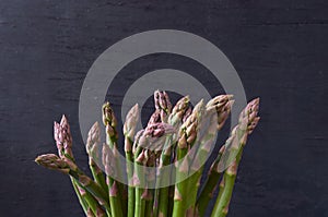 Fresh green asparagus on black wooden background with copy space. Close up view