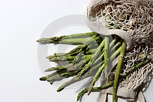 Fresh green asparagus in cotton mesh bag. Healthy living concept.