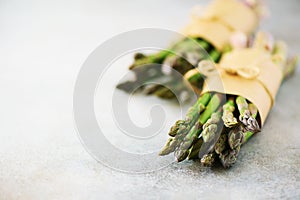 Fresh green asparagus in craft paper on marble background. Banner. Raw, vegan, vegetarian and clean eating concept. Food