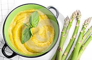 Fresh green asparagus cream soup on white wooden background